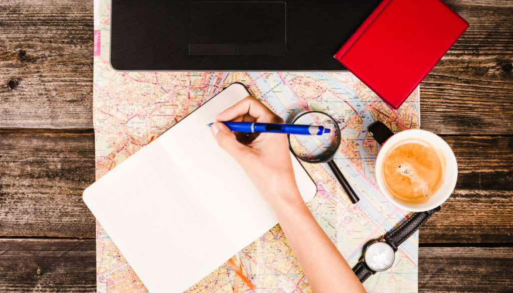 top view of a person writing in a travel diary of his own